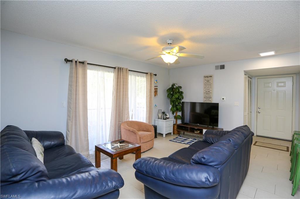 2214 Arbour Walk Circle, Unit 2012 Naples, FL 34109 - Photo 12 of 29 a living room with furniture a fireplace and a flat screen tv