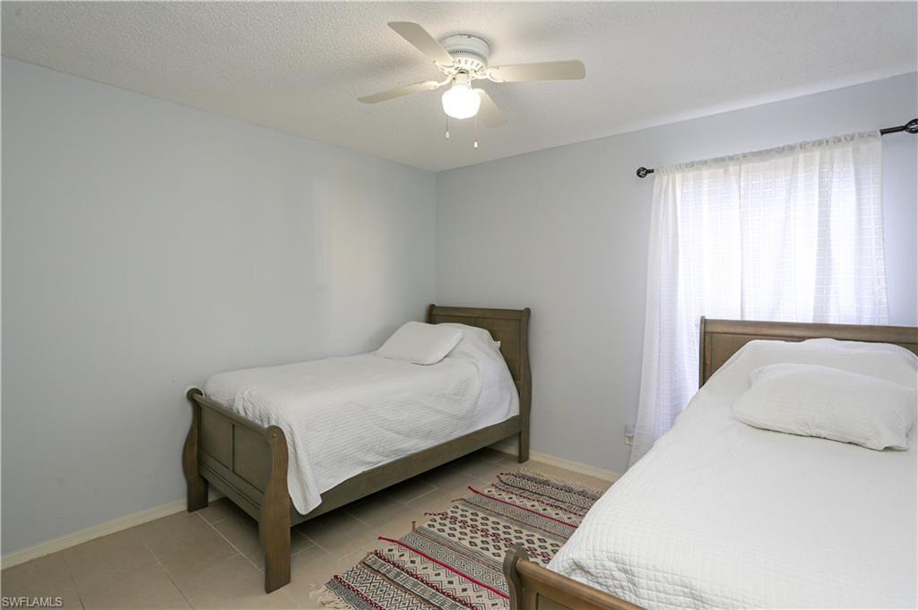 2214 Arbour Walk Circle, Unit 2012 Naples, FL 34109 - Photo 17 of 29 a bedroom with a bed and a chandelier