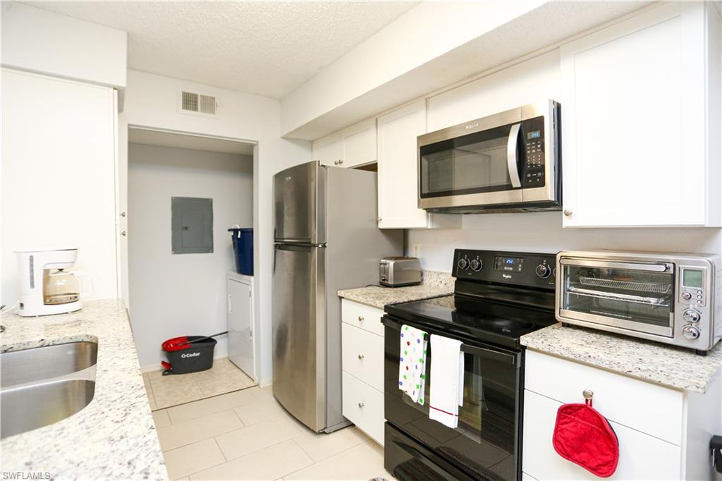 2214 Arbour Walk Circle, Unit 2012 Naples, FL 34109 - Photo 9 of 29 a kitchen with a stove and a microwave