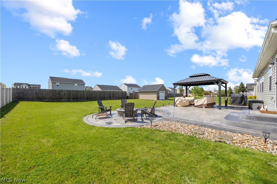 2161 Fowl Road Elyria, OH 44035 - Photo 40 of 46 Expansive backyard featuring a manicured lawn, a stamped concrete patio, a built-in fire pit area, a permanent gazebo, and a privacy fence