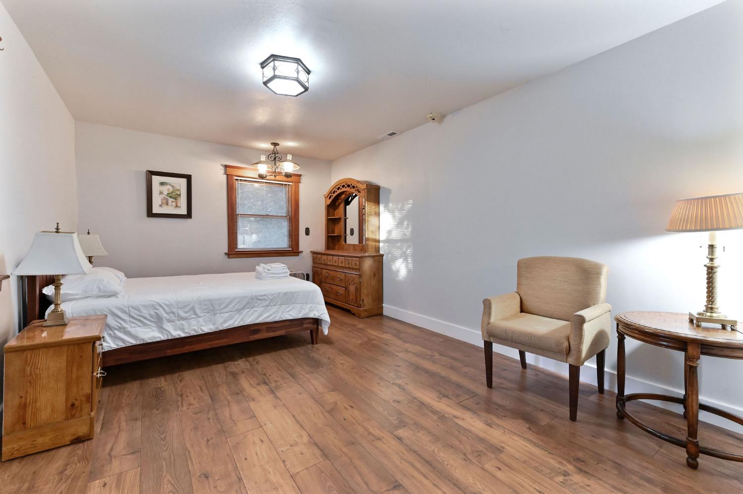 5276 Highway 4 Murphys, CA 95247 - Photo 34 of 69 a spacious bedroom with a bed a desk and chair with wooden floor