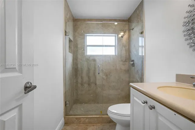 a bathroom with a granite countertop toilet a sink a shower and a mirror