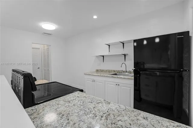 a kitchen with granite countertop a refrigerator a stove a sink a washer and dryer