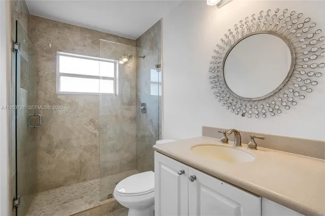 a bathroom with a granite countertop toilet a sink and a mirror