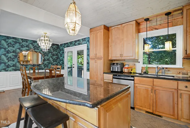 a kitchen with granite countertop a stove a sink dishwasher a dining table and chairs with wooden floor