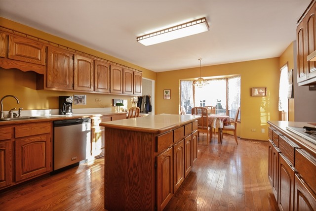 11445 Hummingbird Lane Mokena, IL 60448 - Photo 6 of 10 a kitchen with stainless steel appliances granite countertop a table chairs a stove a sink dishwasher and cabinets with wooden floor