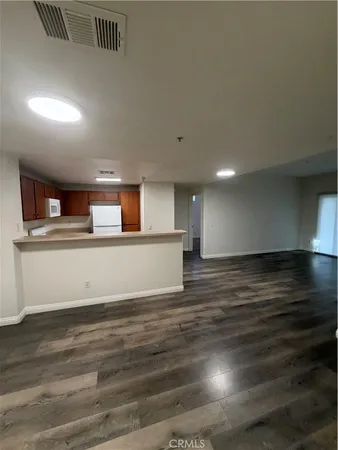 a view of kitchen and empty room with wooden floor