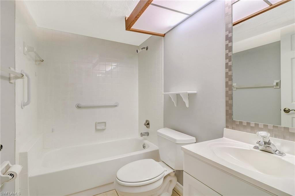 5809 Rattlesnake Hammock Road, Unit 102 Naples, FL 34113 - Photo 17 of 23 a bathroom with a bathtub shower sink vanity mirror and toilet