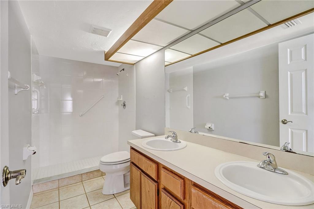 5809 Rattlesnake Hammock Road, Unit 102 Naples, FL 34113 - Photo 18 of 23 a bathroom with a sink a toilet and a large mirror