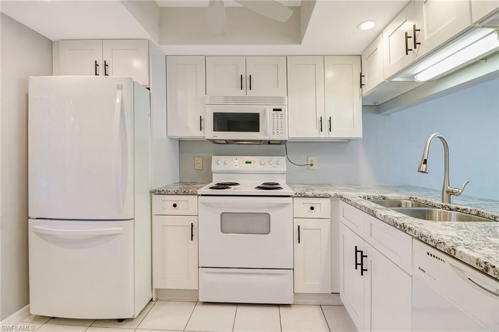 5809 Rattlesnake Hammock Road, Unit 102 Naples, FL 34113 - Photo 3 of 23 a kitchen with white cabinets and white appliances