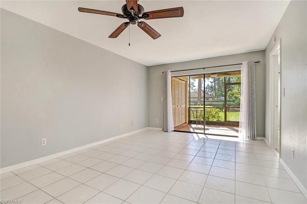 5809 Rattlesnake Hammock Road, Unit 102 Naples, FL 34113 - Photo 8 of 23 an empty room with chandelier fan and windows