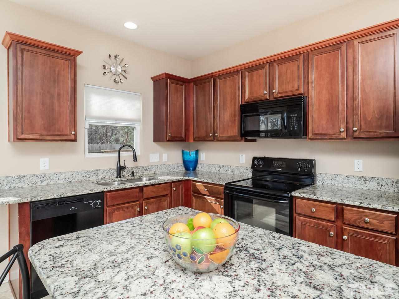 5624 Quitman Trail Raleigh, NC 27610 - Photo 11 of 25 a kitchen with stainless steel appliances wooden cabinets a stove a sink and a microwave