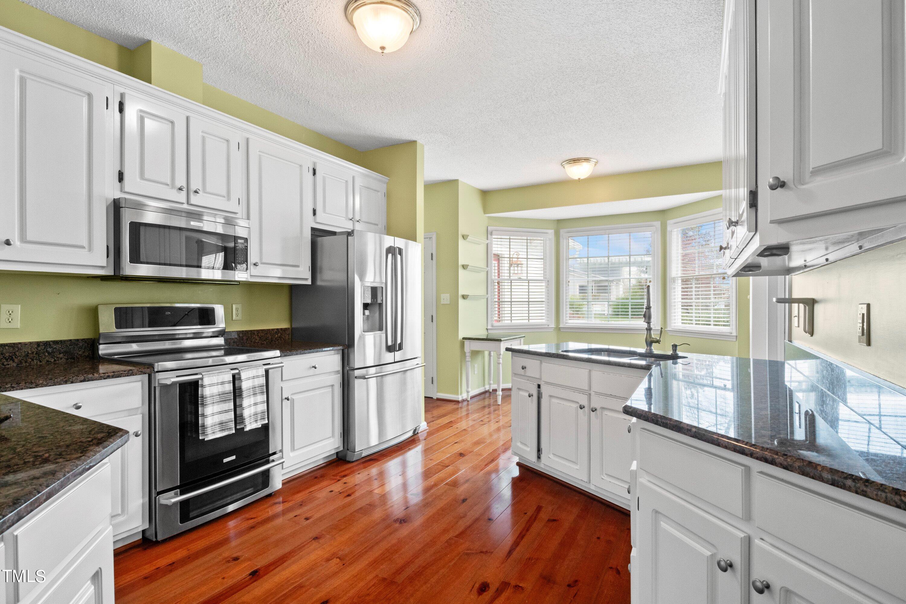 671 Old Evans Road Garner, NC 27529 - Photo 17 of 44 a kitchen with stainless steel appliances white cabinets a sink a stove a refrigerator and microwave