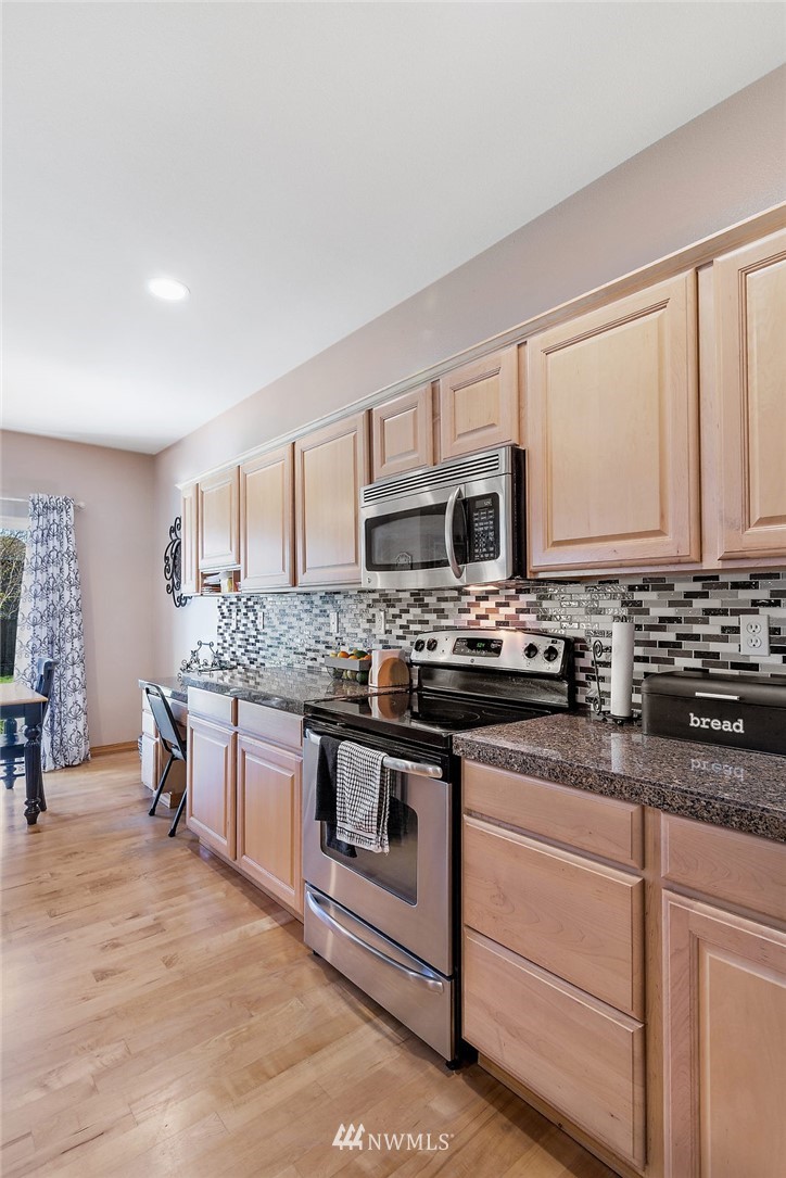 3124 172 Street Southeast Bothell, WA 98012 - Photo 7 of 25 a kitchen with stainless steel appliances granite countertop a stove a sink and a microwave