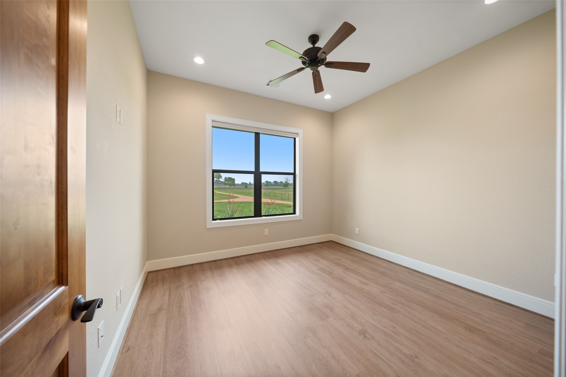 30163 High Spirit Ranch Road Hempstead, TX 77445 - Photo 27 of 49 an empty room with wooden floor chandelier fan and windows