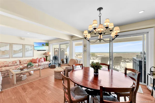a view of a dining room with furniture a chandelier and large windows
