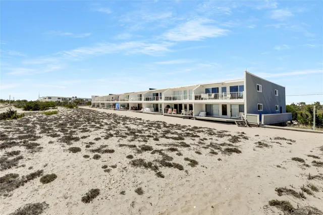 a large white building with a view of house with yard and covered with snow in front of house