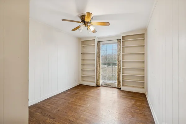 an empty room with wooden floor chandelier fan and windows