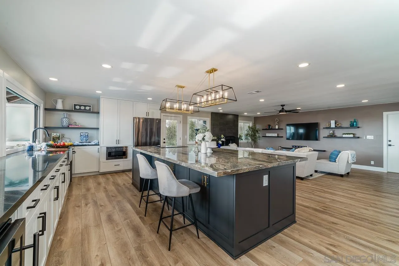 1647 Sleeping Indian Road Fallbrook, CA 92028 - Photo 11 of 48 a kitchen with stainless steel appliances granite countertop a sink dishwasher a stove and a dining table with wooden floor