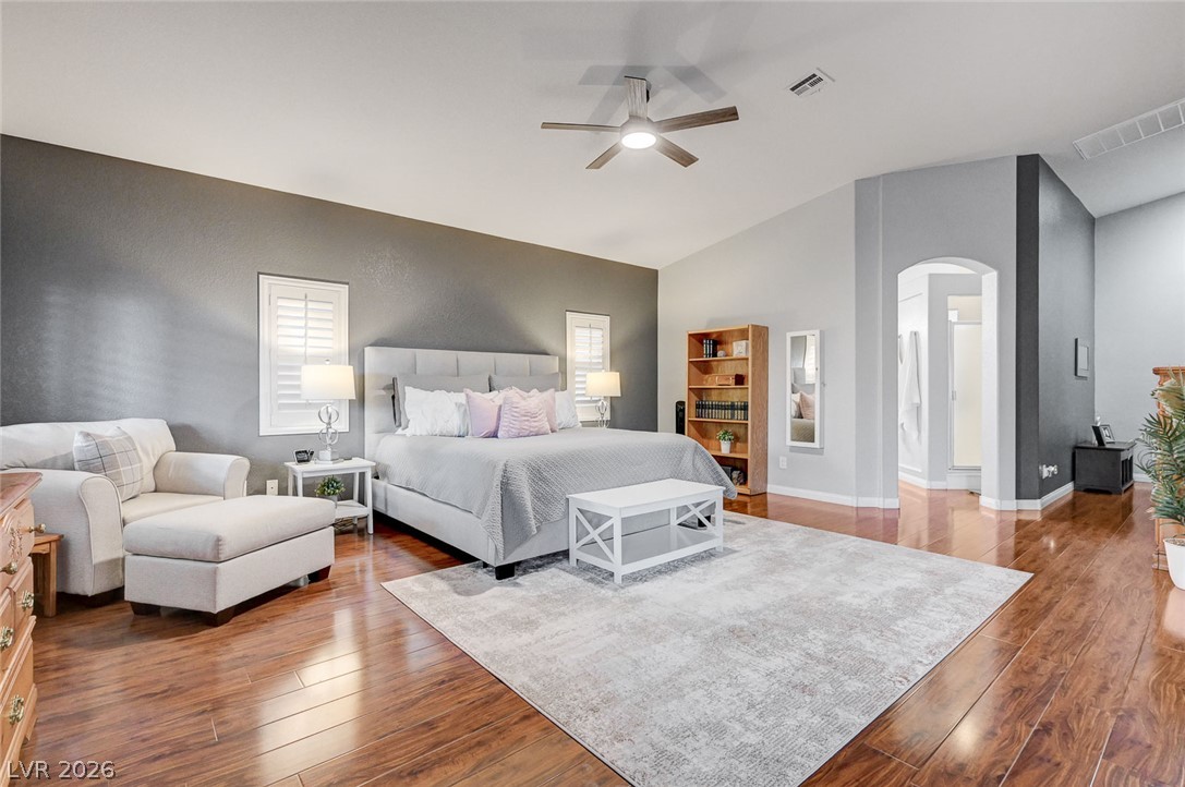 1604 Cattle Ranch Place Henderson, NV 89002 - Photo 35 of 99 Hardwood floors and vaulted ceilings elevate this generously proportioned primary bedroom, complete with a contemporary ceiling fan.