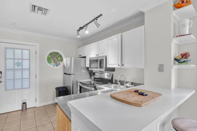 a living room with stainless steel appliances furniture a rug kitchen view and a table