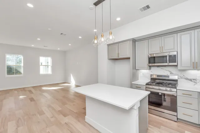 a kitchen with kitchen island white cabinets appliances and a window