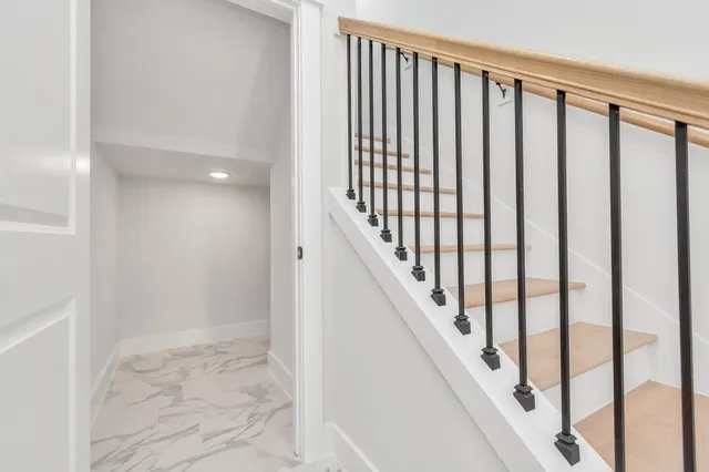 a view of staircase with railing and white walls