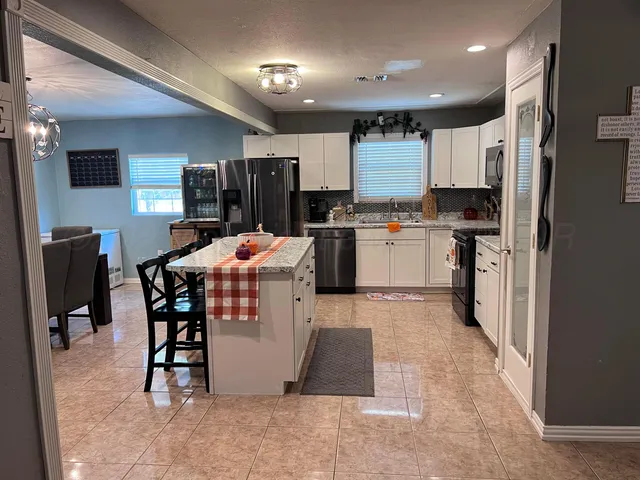 a kitchen with stainless steel appliances kitchen island granite countertop a refrigerator and microwave