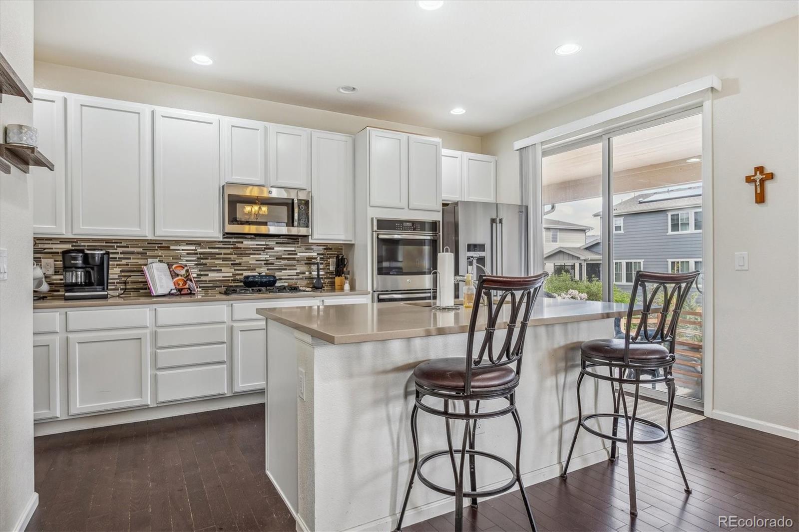 19955 West 93rd Avenue Arvada, CO 80007 - Photo 8 of 33 a kitchen with stainless steel appliances granite countertop a stove a refrigerator a microwave oven a sink with white cabinets and wooden floor