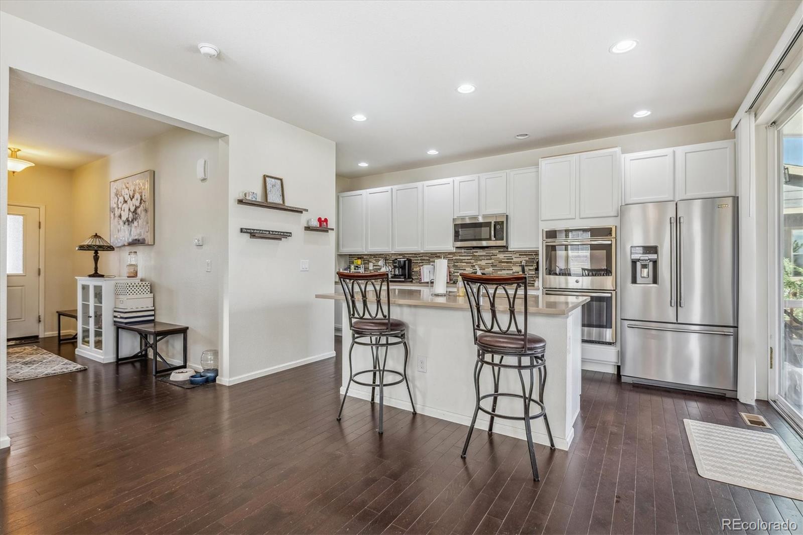 19955 West 93rd Avenue Arvada, CO 80007 - Photo 10 of 33 a kitchen with stainless steel appliances a refrigerator a stove top oven and wooden floors