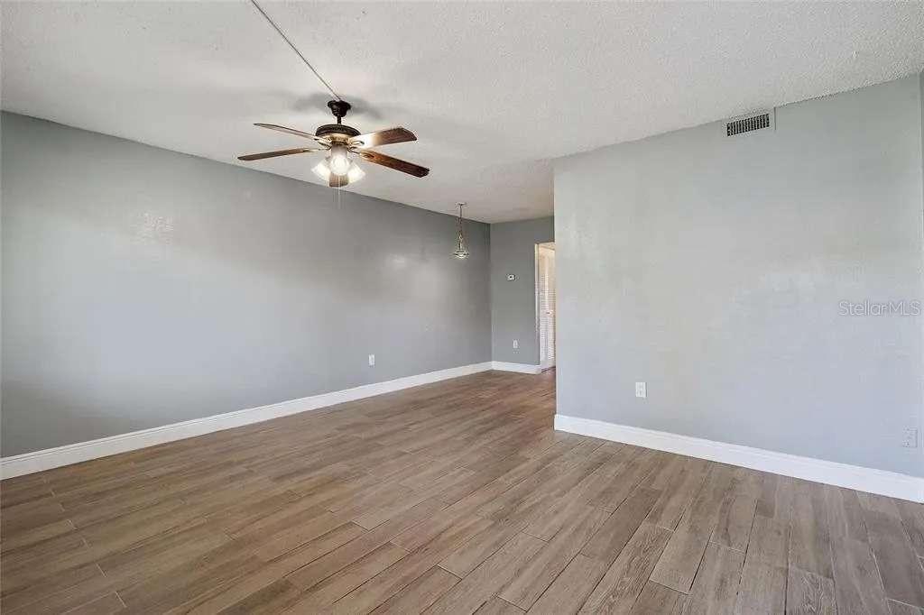 379 47th Avenue North, Unit 103 St. Petersburg, FL 33703 - Photo 11 of 24 an empty room with wooden floor ceiling fan and window
