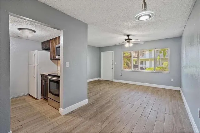 an empty room with wooden floor a ceiling fan and windows