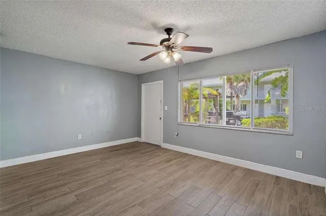 a view of an empty room with wooden floor and a window