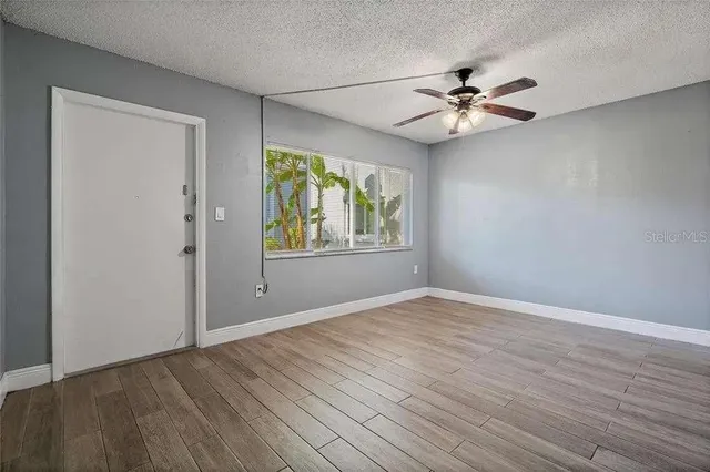 a view of an empty room with window and wooden floor
