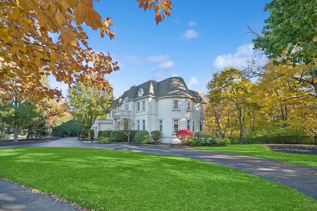 a view of a white house with a big yard and large trees