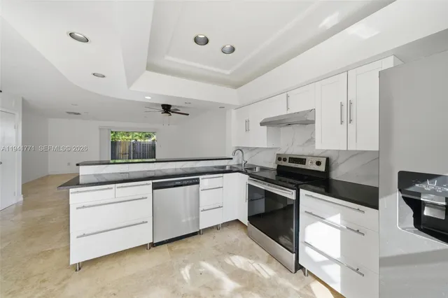 a kitchen with granite countertop white cabinets and white appliances