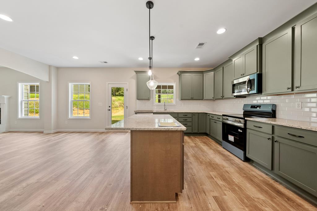 575 Bohannon Road Grantville, GA 30220 - Photo 8 of 33 a large kitchen with stainless steel appliances granite countertop a stove a sink dishwasher and a refrigerator with wooden floor