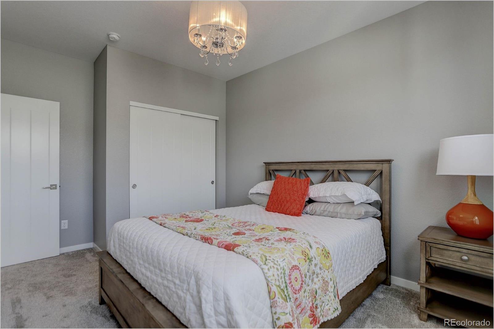 8928 Delacorte Street Highlands Ranch, CO 80129 - Photo 15 of 26 a bedroom with a bed and a lamp on dresser