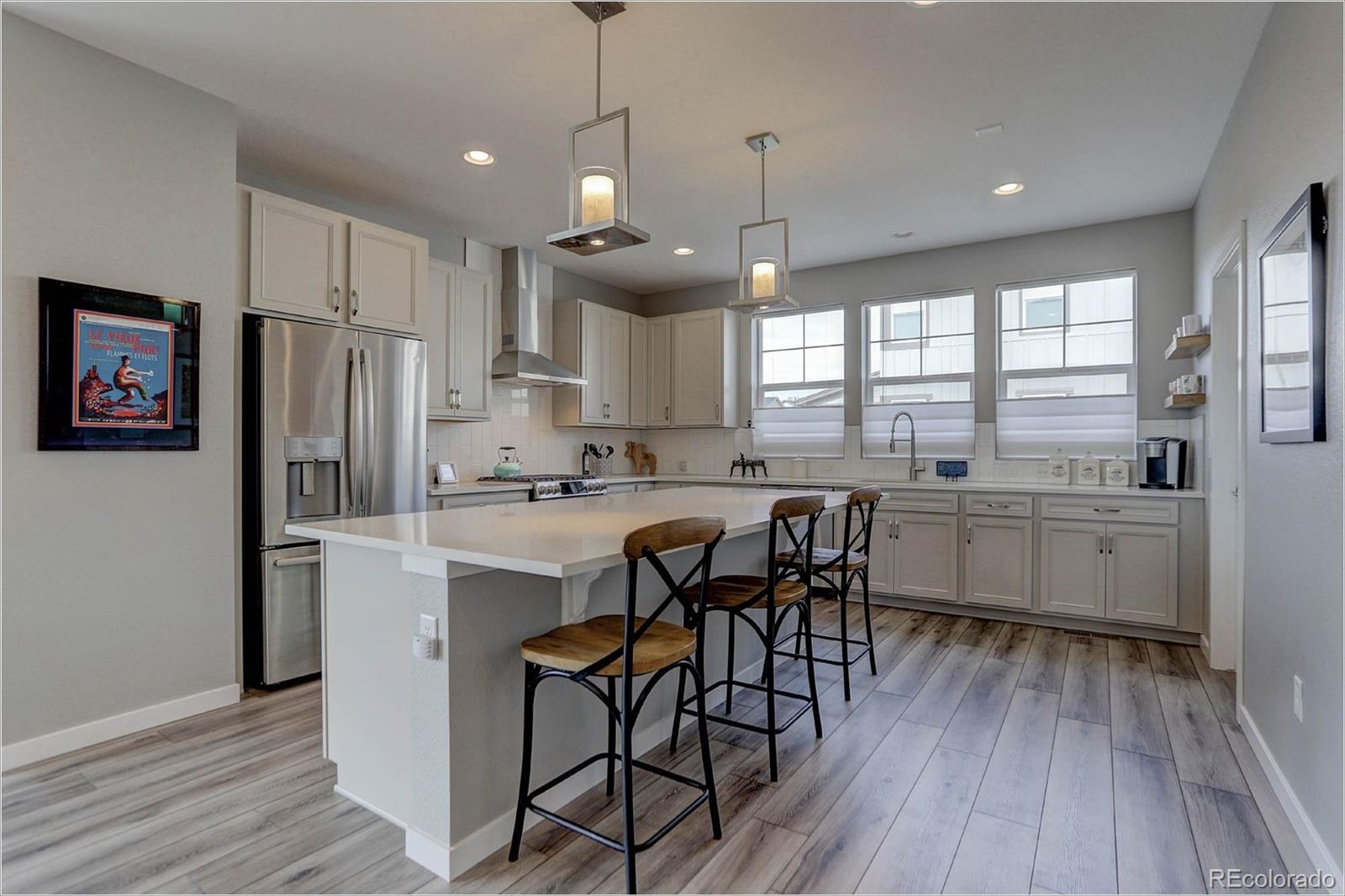 8928 Delacorte Street Highlands Ranch, CO 80129 - Photo 6 of 26 a kitchen with stainless steel appliances granite countertop a refrigerator a sink dishwasher a stove and white cabinets with wooden floor