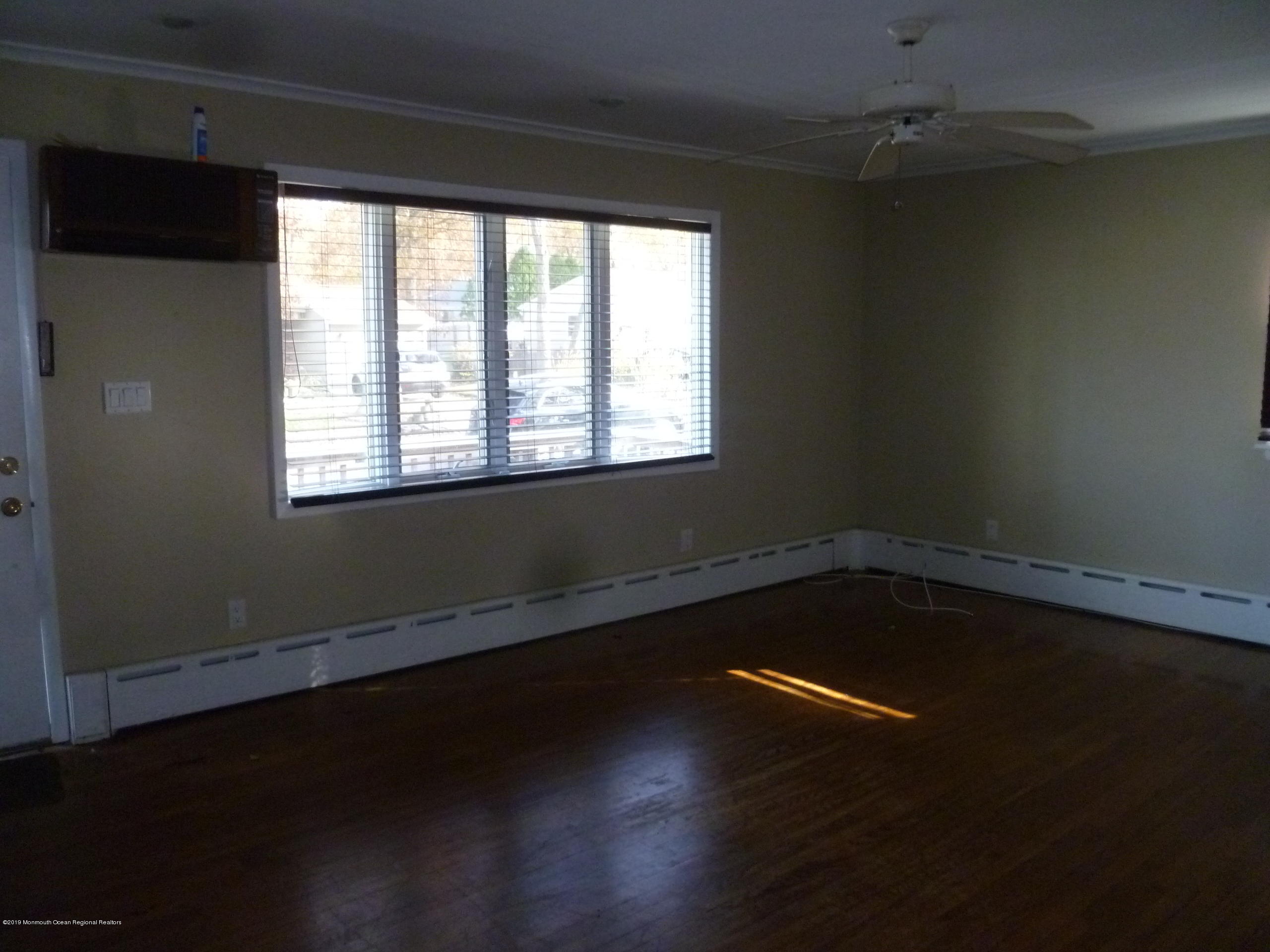 416 Ely Road Neptune Township, NJ 07753 - Photo 6 of 13 an empty room with wooden floor and windows with curtains
