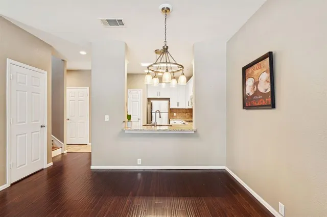 a view of a hallway with wooden floor and chandelier