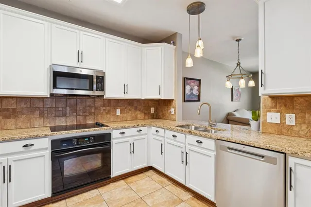 a kitchen with stainless steel appliances granite countertop a sink a stove a microwave and wooden cabinets