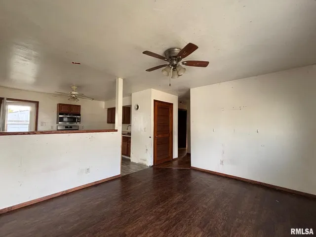 an empty room with wooden floor and a ceiling fan