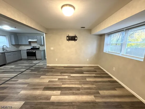 a view of a kitchen with kitchen island a sink wooden floor and a large window