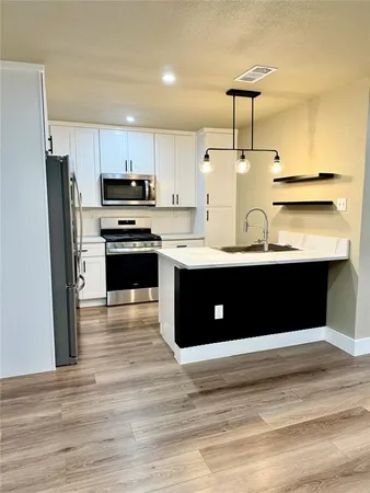a kitchen with stainless steel appliances a sink cabinets and wooden floor