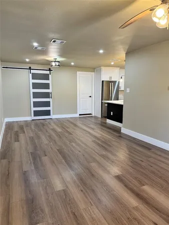a view of empty room with wooden floor and kitchen view