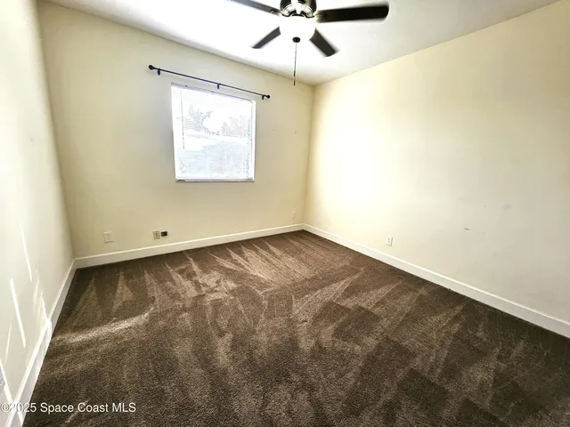 an empty room with a window and a ceiling fan