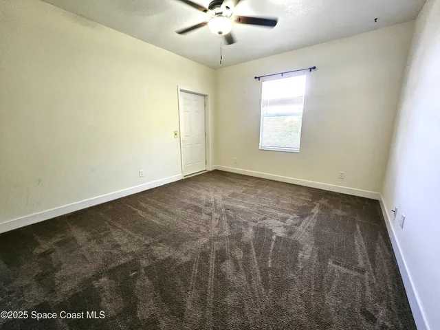 an empty room with a window and a ceiling fan