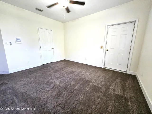 an empty room with a ceiling fan and carpet