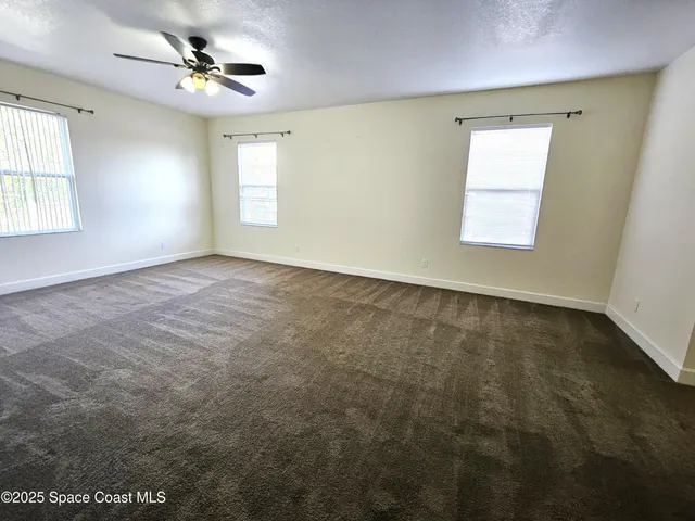 an empty room with windows and ceiling fan